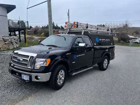 Sherwood’s black F-150 with black canopy, blue branding and aluminum ladder rack