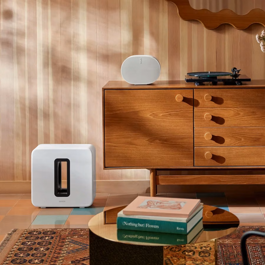 White Sonos subwoofer beside a wooden cabinet in a living room